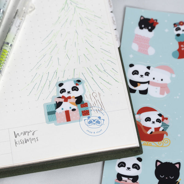 Sticker placed on a planner featuring Pandasal the panda and a fluffy kitten hiding in a gift box. In the background, you can see the original stickersheet with various panda and kitten poses